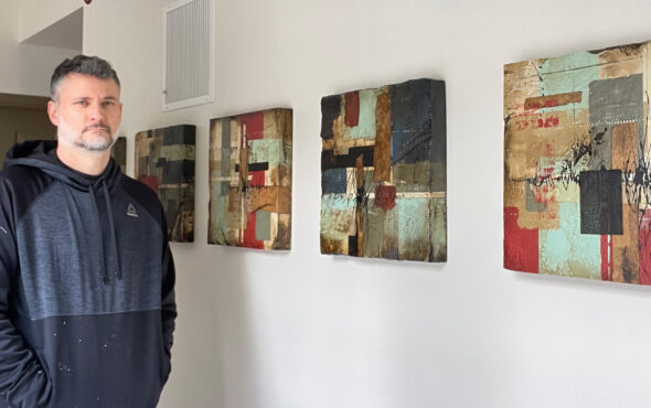 Artist Domenick Naccarato stands in front of a series of his abstract collage paintings.